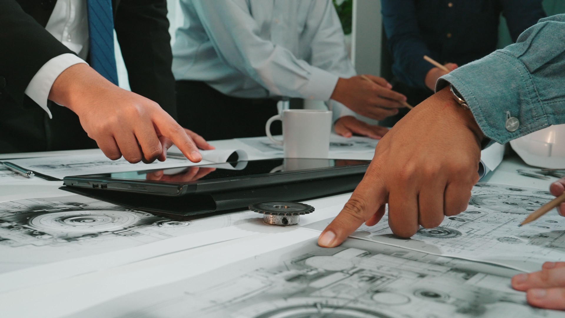 Collaborative Workplace Meeting with Diverse Professionals Analyzing Project Plans and Drawings with Digital Tablet on Desk SACTR